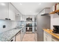 Modern kitchen featuring granite countertops, stainless steel appliances, white subway tile backsplash, and wood-look flooring at 6851 Roswell Rd # M12, Sandy Springs, GA 30328
