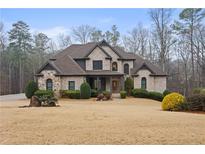 Elegant two-story brick home boasts a manicured lawn and mature trees, offering timeless curb appeal at 3591 Lochwolde Ln, Snellville, GA 30039