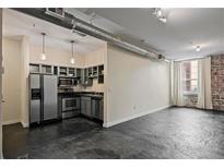 Spacious living room with kitchen, brick wall, natural light, and modern stainless steel appliances at 800 Peachtree Ne St # 8508, Atlanta, GA 30308