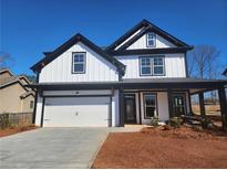 Stunning new construction featuring a modern farmhouse exterior with a welcoming front porch and a two-car garage at 1064 Eastview Ne Rd, Conyers, GA 30012