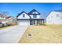 Two-story home featuring a covered front porch, attached two-car garage, and a well-manicured lawn at 1064 Eastview Ne Rd, Conyers, GA 30012