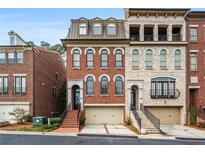 Charming brick townhome featuring arched windows, a two-car garage, and inviting entryway staircase at 3641 Broughton Se Cir, Atlanta, GA 30339