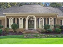 Charming brick home featuring a symmetrical design, arched windows, a beautiful entrance, and landscaped front yard at 1585 Lazy River Ln, Sandy Springs, GA 30350