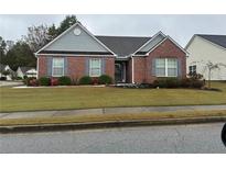 Charming brick home featuring manicured landscaping, gray shutters, and a well-maintained lawn at 714 Village Ln, Loganville, GA 30052