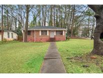 Charming brick home featuring a well-maintained front yard with mature trees at 1678 Capistrana Pl, Decatur, GA 30032