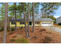 Charming yellow ranch-style house with green trim, nestled among tall pine trees and a well-manicured yard at 2142 Graystone Pkwy, Grayson, GA 30017