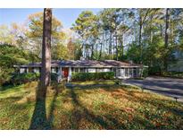 Charming single-story home with a red door and a well-manicured lawn surrounded by mature trees and a large driveway at 3151 Rilman Nw Rd, Atlanta, GA 30327
