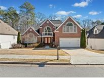 Charming two-story red brick home with an attached two-car garage and a well-manicured front yard at 1034 Fairview Club Cir, Dacula, GA 30019