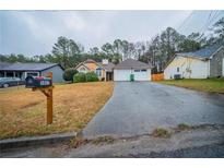 Charming single-story home with a well-manicured lawn and a long driveway leading to an attached garage at 5087 Donnell Way, Decatur, GA 30035