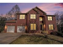 Charming brick two-story home featuring a two-car garage, well-manicured lawn, and classic architectural details at 10950 Glenhurst Pass, Duluth, GA 30097