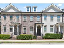 Townhomes with brick facade, dark windows, front porch, and manicured landscaping at 3879 Glenview Club Ln, Duluth, GA 30097