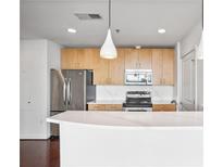 Modern kitchen features stainless steel appliances, wooden cabinets, white countertops, and stylish pendant lighting at 361 17Th Nw St # 922, Atlanta, GA 30363