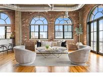 Bright living room boasts exposed brick, hardwood floors, large windows and stylish modern furniture at 3235 Roswell Ne Rd # 917, Atlanta, GA 30305