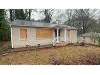 Single-story home with a covered porch and boarded-up windows; in need of renovation at 1969 Oak Valley Rd, Decatur, GA 30035