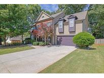 Charming two-story home with a well-manicured lawn, beautiful landscaping, and an attached two-car garage at 2295 Hemrick Rd, Cumming, GA 30041