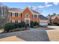 Beautiful two-story brick home with a well-manicured lawn, attached two car garage and mature landscaping at 9470 Dominion Way, Alpharetta, GA 30022