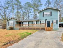 Inviting split-level home featuring a spacious front porch, black shutters, and an asphalt driveway at 3898 Panthersville Rd, Ellenwood, GA 30294