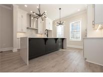 Bright kitchen with modern light fixtures, white cabinetry, and large island with breakfast bar at 275 Briscoe Way # 3, Alpharetta, GA 30009
