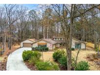 Ranch style home with a long drive way nestled amongst the trees and an attached garage at 221 Shadowood Ln, Peachtree City, GA 30269