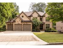 Beautiful brick home with a three-car garage and well-manicured lawn and mature landscaping at 204 Fernwood Pl, Woodstock, GA 30188