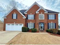 Charming two-story red brick home with a well-manicured lawn and a two-car garage at 6765 Crofton Dr, Alpharetta, GA 30005