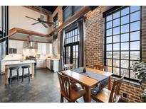 Open-concept living room with exposed brick walls, large windows, and a modern kitchen at 5434 Peachtree Rd # 115, Chamblee, GA 30341