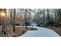 Unique home design featuring a circular roofline, attached two-car garage and a long concrete driveway at 100 Silverbell Ct, Roswell, GA 30075