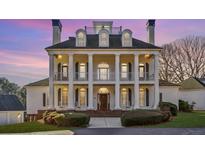 Stately home with a white exterior, multiple columns, and manicured landscaping at 2595 Ross Rd, Snellville, GA 30039