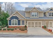 Charming townhome with a two-car garage, beautifully landscaped yard, and a mix of blue and brown siding at 1675 Water Vista Ct # 4501, Cumming, GA 30041