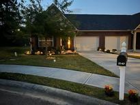 Charming home exterior featuring a lush lawn, a two-car garage, and a well-lit driveway and walkway at 2147 Red Oak Cir, Union City, GA 30291