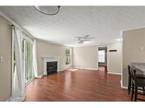 Spacious living room with wood floors, fireplace, fan, and sliding door with curtains at 1371 Keys Lake Ne Dr, Brookhaven, GA 30319