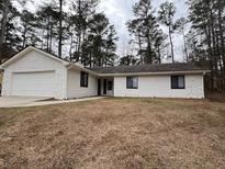 Charming single-story home features a large garage and a well-maintained front yard surrounded by mature trees at 1449 Albans Ct, Lithonia, GA 30058