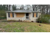 Exterior of a one-story home featuring a brick facade, black shutters, and boarded-up windows at 1963 Oak Valley Rd, Decatur, GA 30035