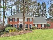 Charming two-story red brick home with a manicured lawn and mature trees at 2055 Pearwood Path, Roswell, GA 30076