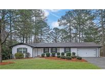 Charming ranch-style home featuring a white painted brick facade, complemented by lush green lawn and mature trees at 4150 Lower Roswell Rd, Marietta, GA 30068