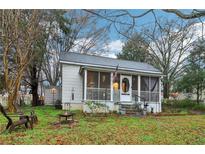 Charming home featuring a quaint screened-in porch and mature trees in a well-maintained front yard at 1610 Elm Ne St, Conyers, GA 30012