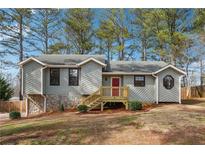 Charming single-Gathering home features a stone foundation, gray siding, and a red front door with inviting wooden steps at 3640 Barbara Dr, Douglasville, GA 30135