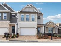 Charming two-story home with gray siding, a white brick facade, and a two-car garage with a brick paver driveway at 642 Stickley Oak Way, Woodstock, GA 30189