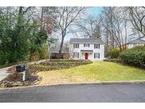 Charming two-story home with a landscaped front yard, complemented by black shutters and a red front door at 970 Winding Creek Trl, Atlanta, GA 30328