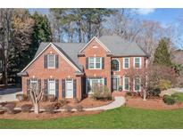 Charming brick home featuring manicured lawn, gray roof, black shutters, and classic architectural details at 733 Vinings Estates Se Dr, Mableton, GA 30126