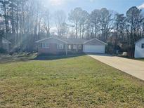 Charming single-story home featuring a well-maintained lawn, brick accents, and an attached two-car garage at 4446 Frontier Way, Sugar Hill, GA 30518