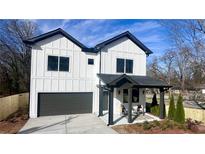 Charming two-story home boasts a modern design with a gray garage door and covered porch at 3128 Cedar St, Scottdale, GA 30079