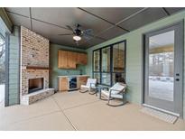 Inviting outdoor living space featuring a brick fireplace and comfortable seating area with wet bar at 472 Price Rd, Carrollton, GA 30116