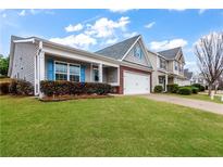 Charming home featuring a lush lawn, manicured hedges, blue shutters, and a convenient two-car garage at 521 Gardenview Rd, Canton, GA 30114
