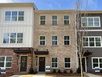 Three-story townhomes showing brick and neutral siding, with black door and window accents at 5459 Blossomwood Sw Trl, Mableton, GA 30126