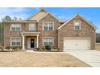 Charming two-story brick home featuring a manicured lawn and attached two-car garage at 10 Tabor Trce, Oxford, GA 30054