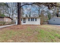 Charming white brick home with black shutters and mature trees in a quiet residential neighborhood at 895 Mercury Nw Dr, Atlanta, GA 30331