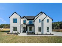 Stunning white brick home featuring black trim, a manicured lawn, and professional landscaping at 3825 Hall Rd, Dacula, GA 30019