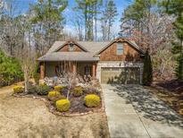 Charming home featuring a stone and cedar shake facade, two-car garage, and beautifully landscaped front yard at 114 Oakwind Pkwy, Canton, GA 30114