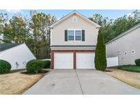 Charming home featuring a two-car garage, complemented by lush green landscaping and mature trees at 158 Oak Grove Pl, Acworth, GA 30102
